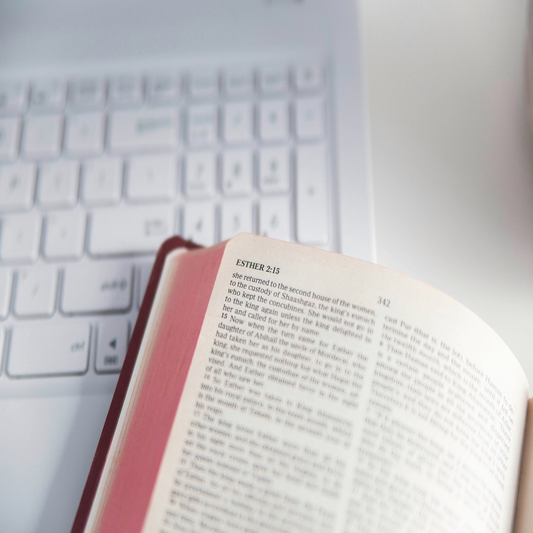 Bible sitting on top of a open white laptop.